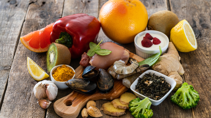 Huîtres, ail, poivron, yaourt, agrumes et autres aliments sur une table en bois.