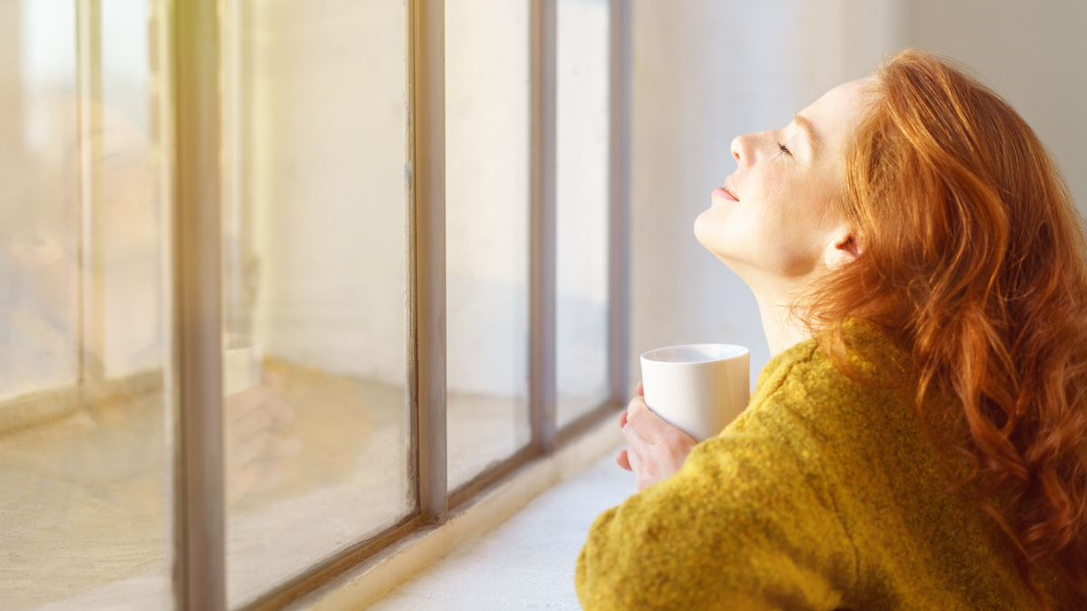 Jeune femme rousse qui prend le soleil derrière une vitre